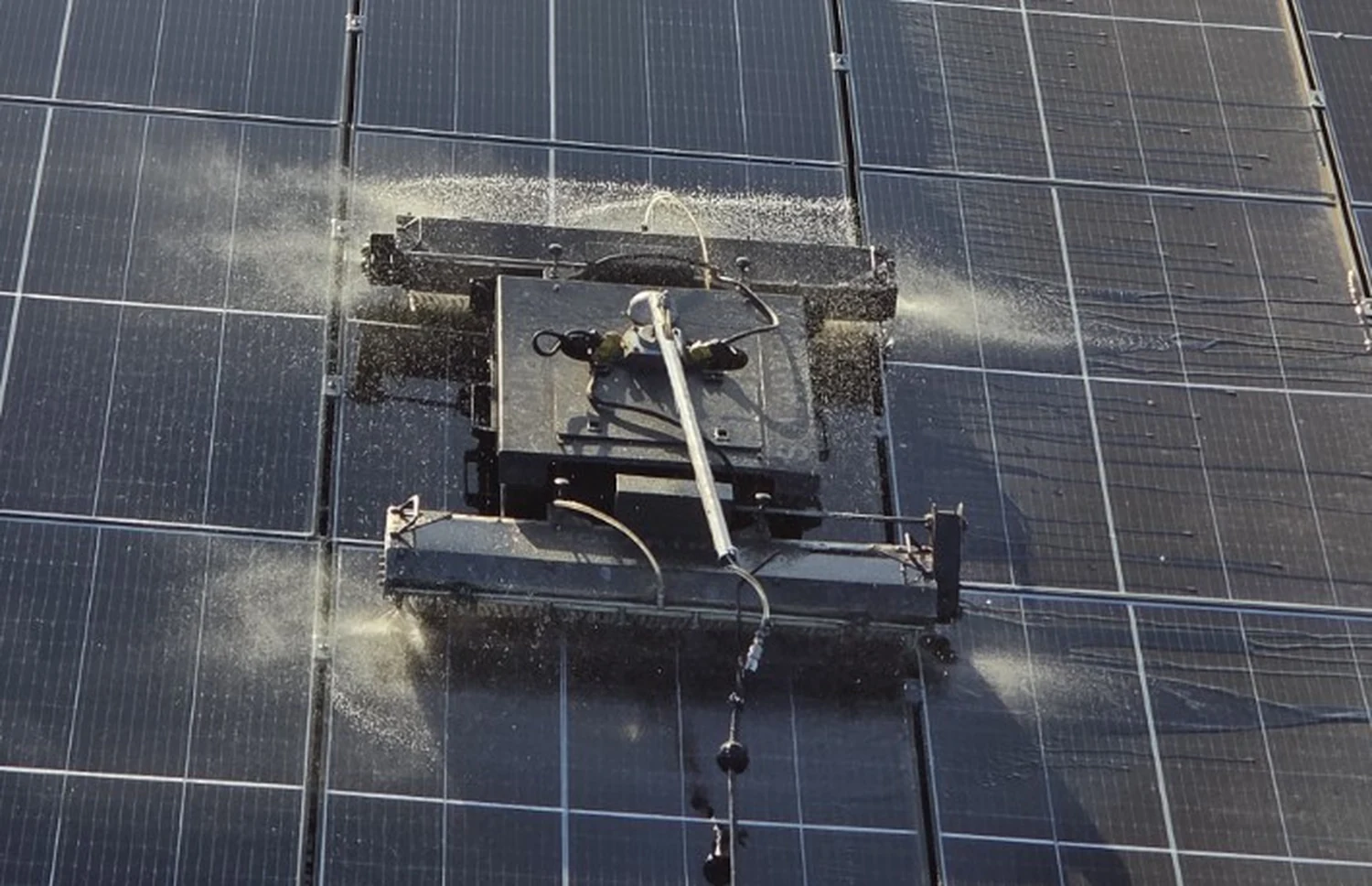 Vue rapprochée du robot Solartrax nettoyant des panneaux photovoltaïques avec pulvérisation d'eau